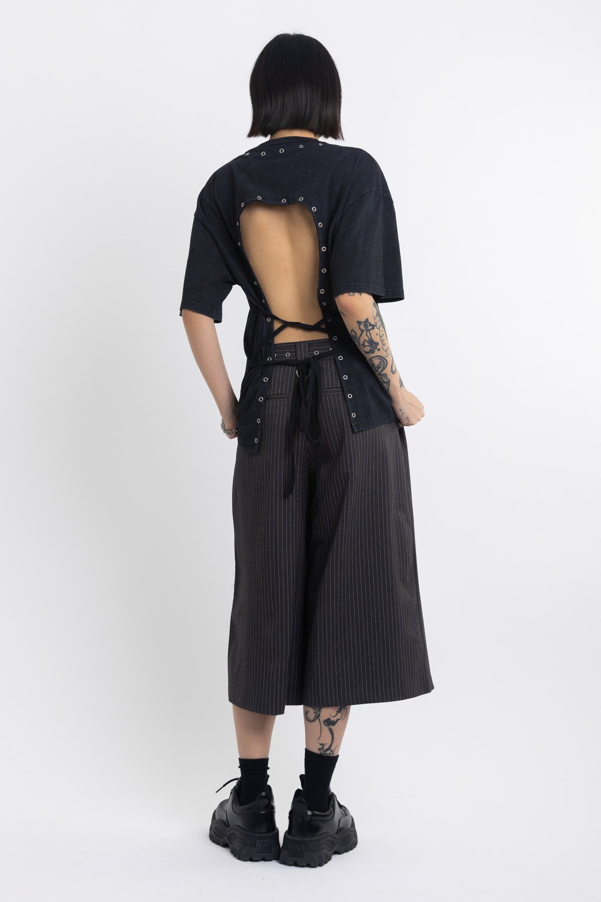 Black oversized t-shirt with open back and eyelet studs, worn by model