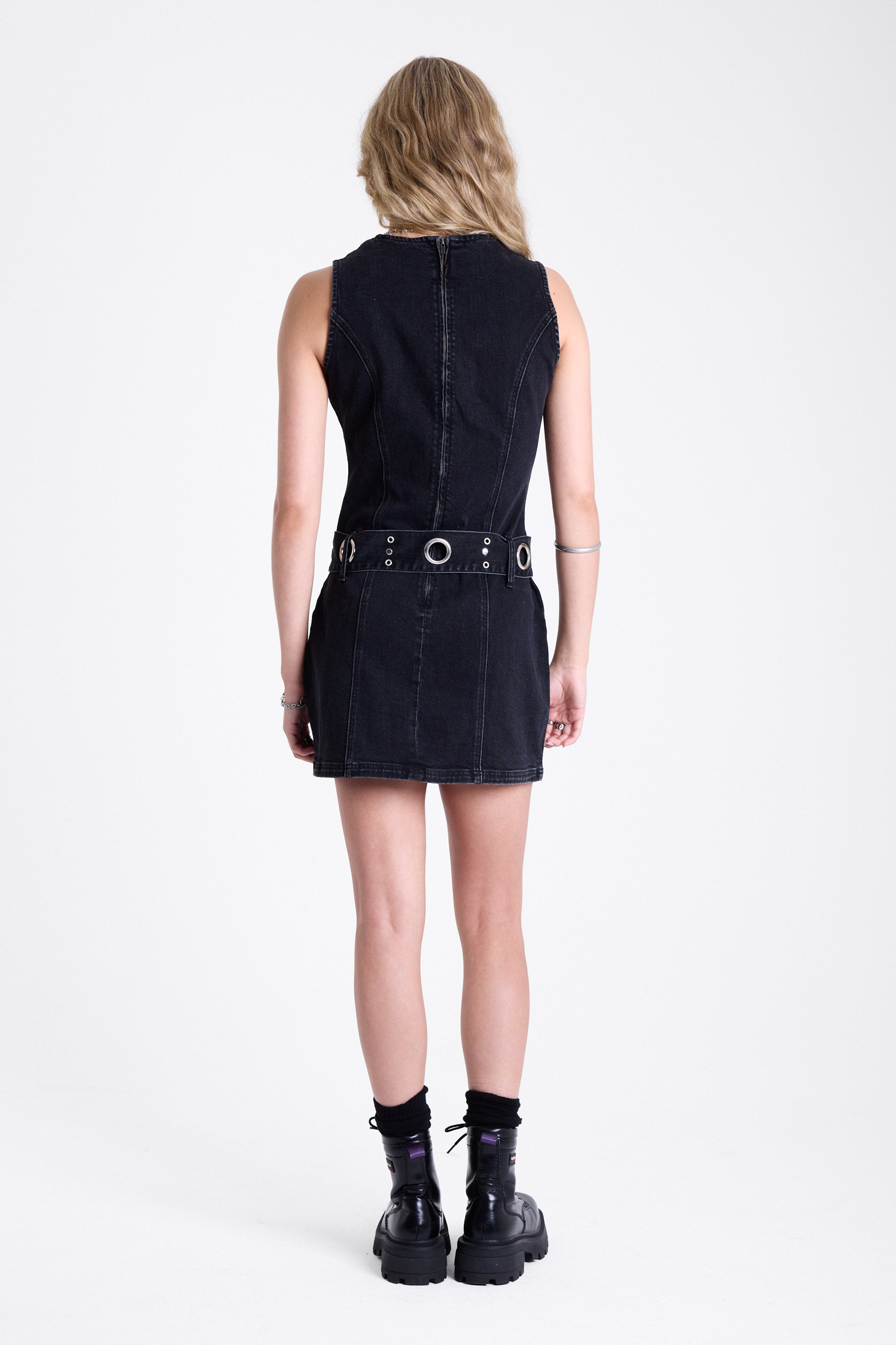 Black denim mini dress with silver trigger clasp eyelet detail belt, worn by model