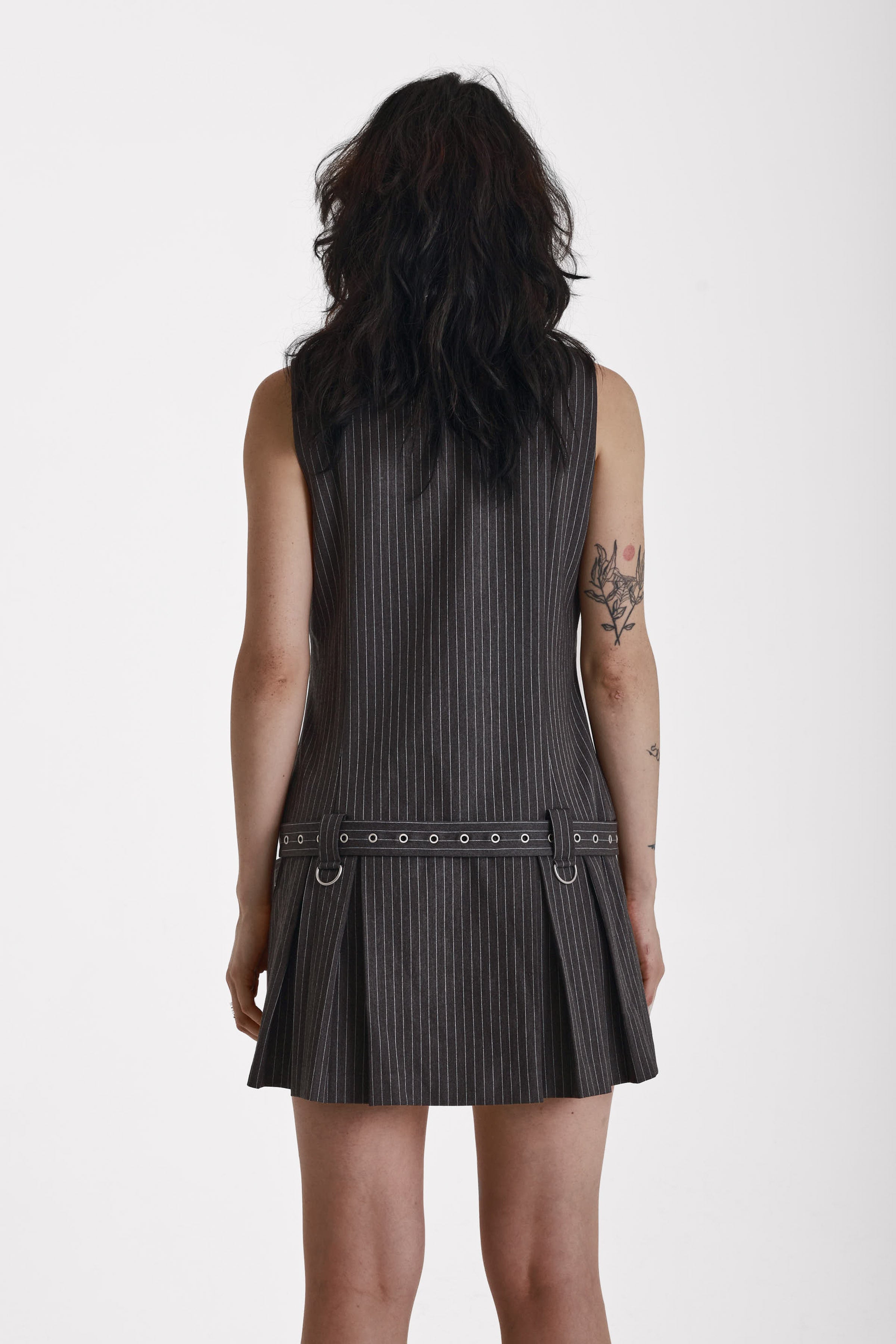 Grey pinstripe zip through mini dress with pleated skirt and silver eyelet belt and D-ring hardware, worn by model