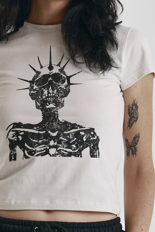 Ecru baby tee with black skeleton skull graphic print, worn by model