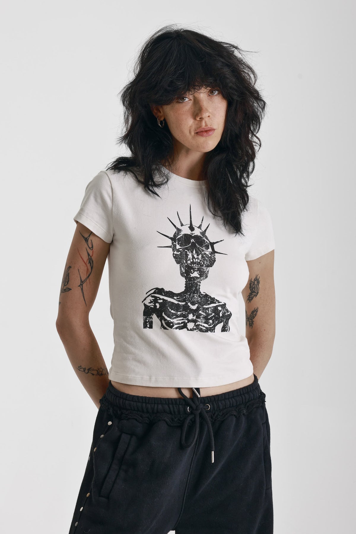 Ecru baby tee with black skeleton skull graphic print, worn by model