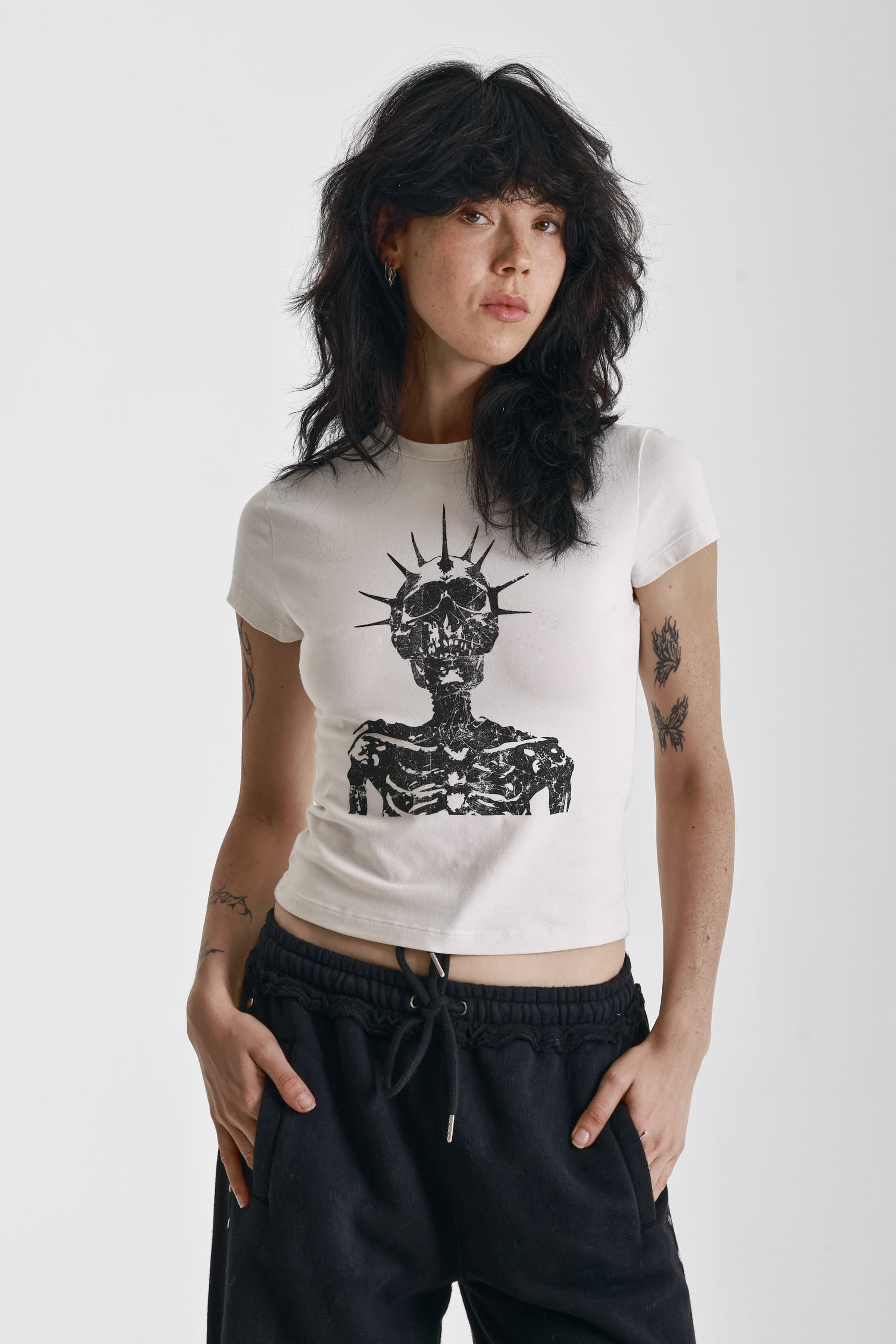 Ecru baby tee with black skeleton skull graphic print, worn by model
