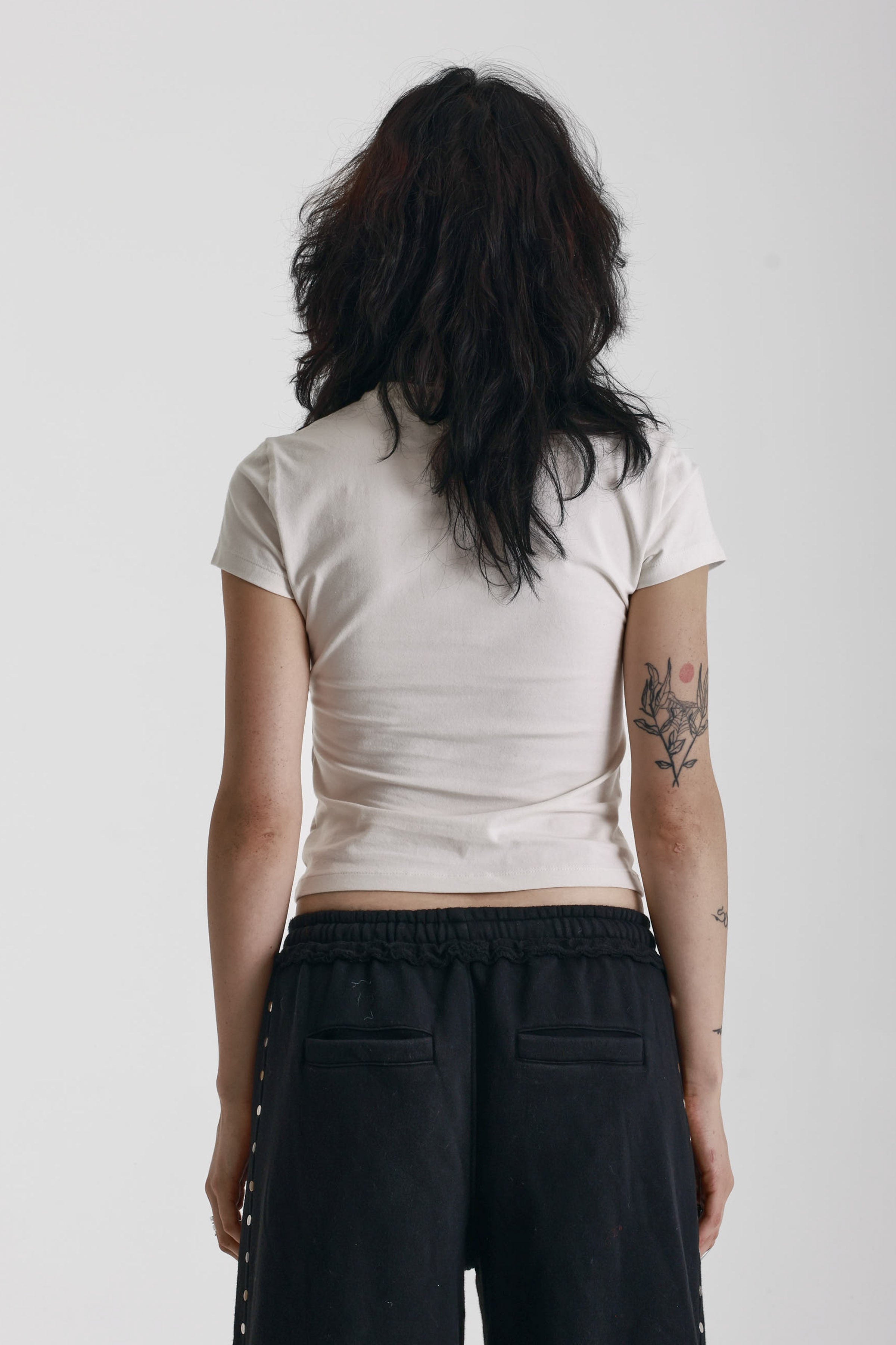 Ecru baby tee with black skeleton skull graphic print, worn by model