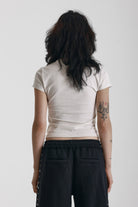Ecru baby tee with black skeleton skull graphic print, worn by model