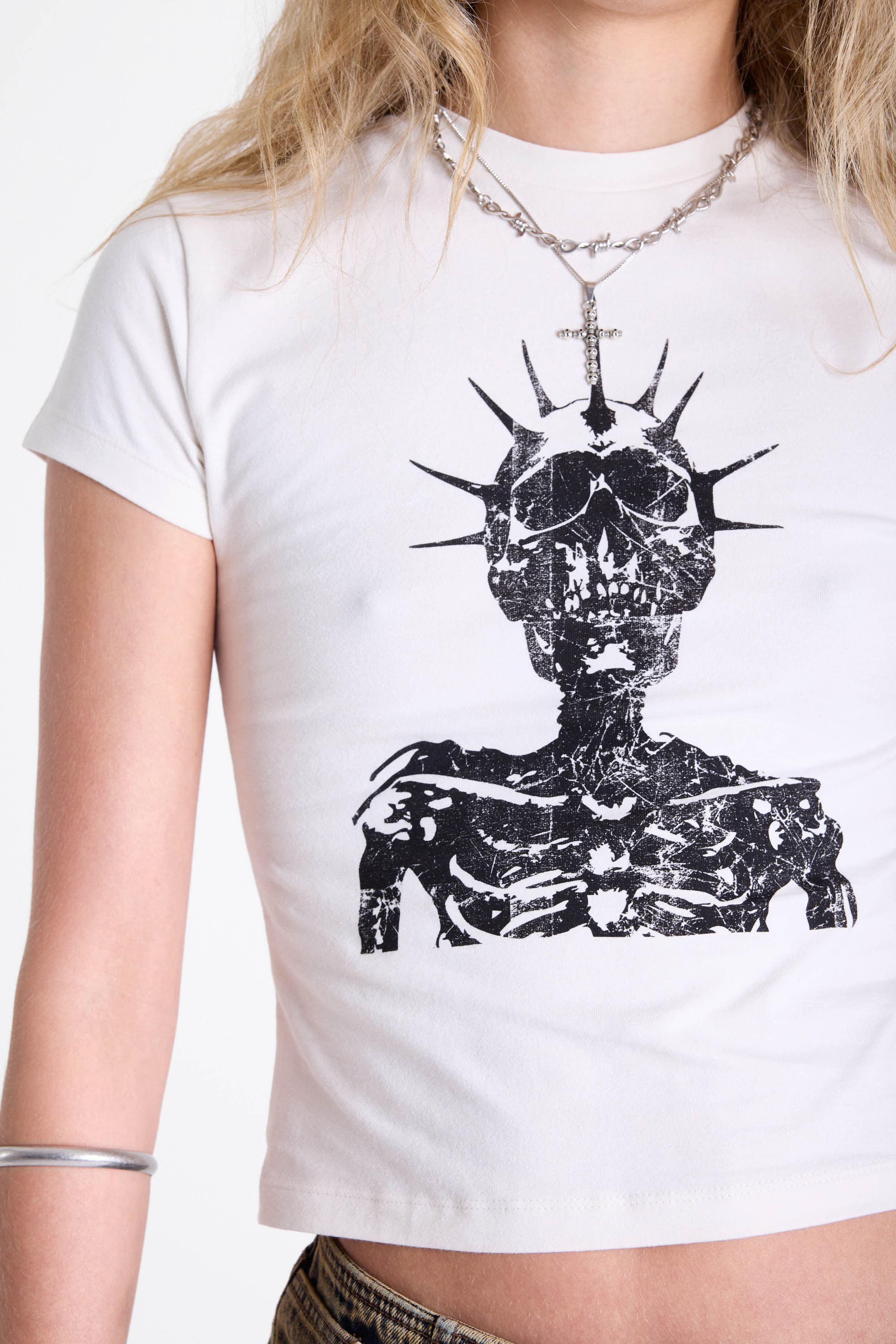 White shrunken baby t-shirt with distressed skull skeleton graphic print, worn by model